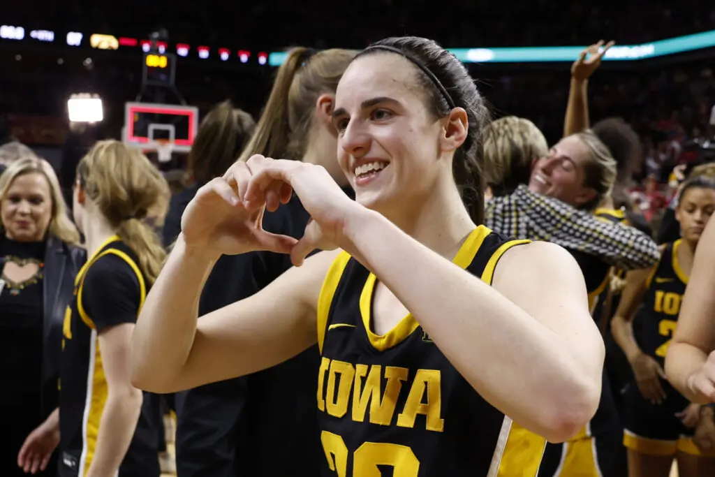 Former Iowa star Caitlin Clark makes a heart sign after an NCAA game.