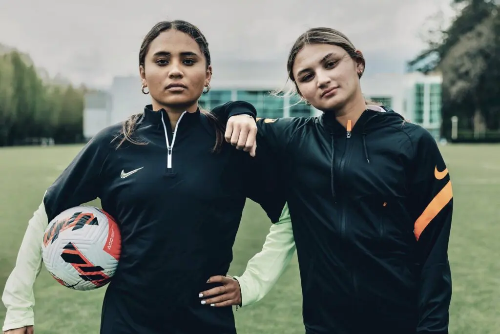 USWNT and Angel City stars Alyssa and Gisele Thompson pose with a soccer ball.