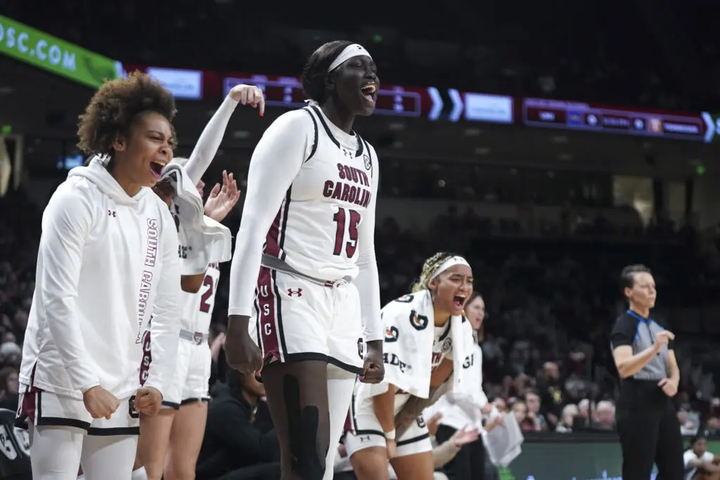 Tessa Johnson, Adhel Tac, and Te-Hina Paopao cheer on their South Carolina teammates during an SEC NCAA college basketball game.