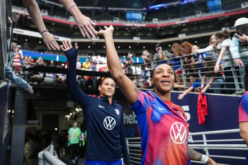 USWNT stars Crystal Dunn and Lynn Biyendolo greet fans as they enter the pitch before a 2025 SheBelieves Cup match.
