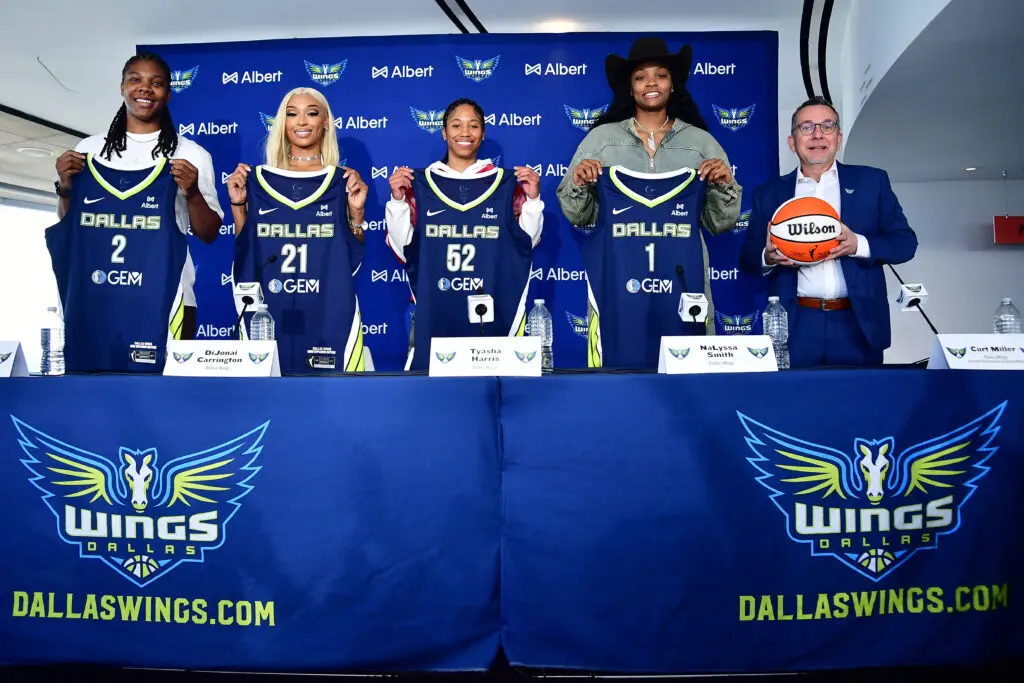 GM Curt Miller poses with Dallas Wings stars Myisha Hines-Allen, DiJonai Carrington, Tyasha Harris, and NaLyssa Smith at a press conference.