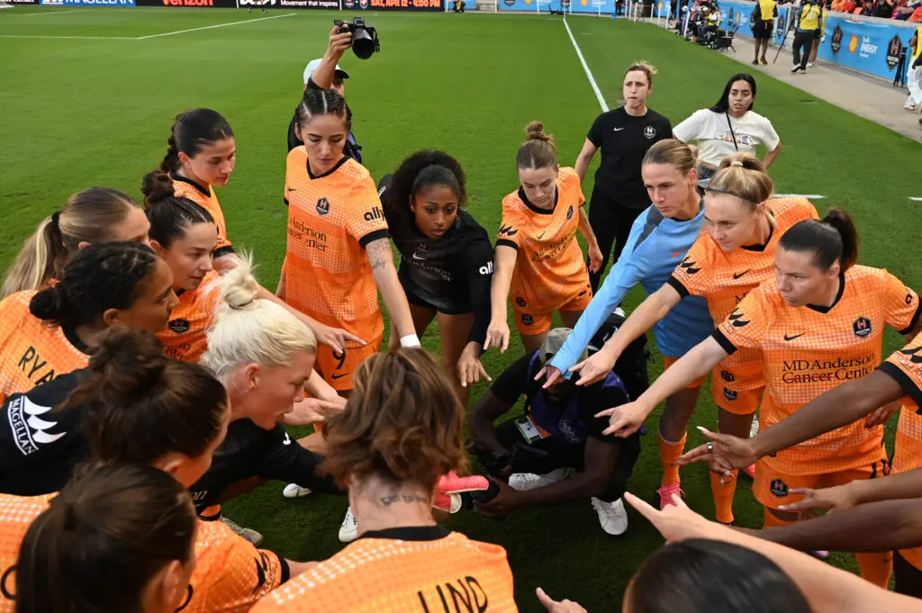 Houston Dash players huddle before a 2025 NWSL match against Gotham FC.