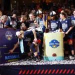 UConn star Paige Bueckers slaps the team's name in the championship spot after defeating South Carolina in Sunday's 2024/25 NCAA basketball title game.