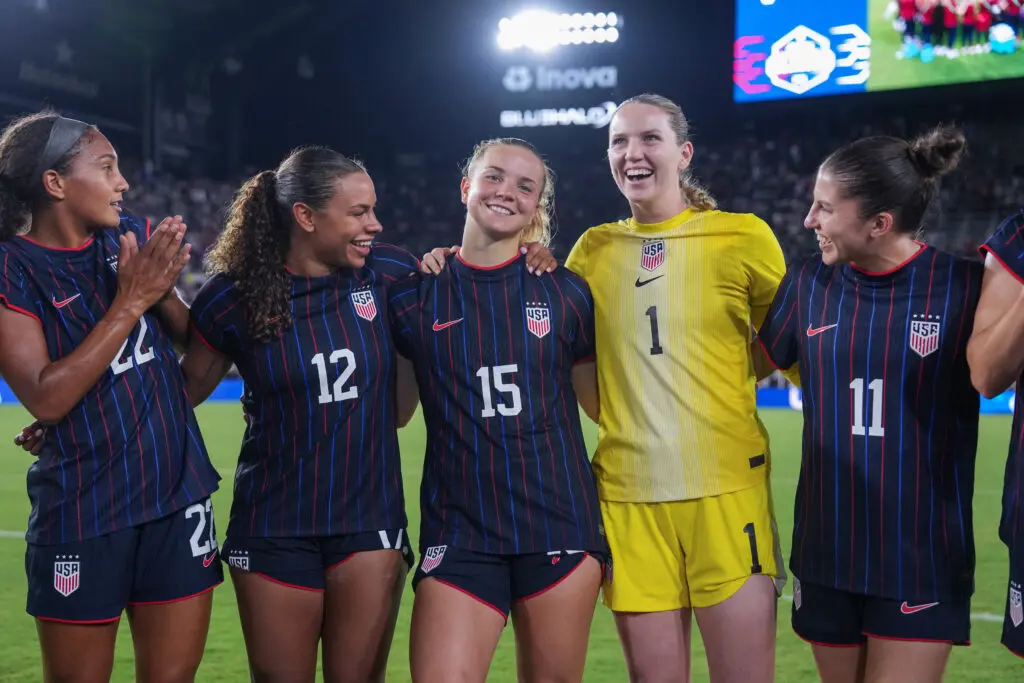Yazmeen Ryan, Michelle Cooper, Claire Hutton, Mandy McGlynn, and Izzy Rodriguez and the rest of the USWNT huddle after their July 2025 friendly win over Canada.