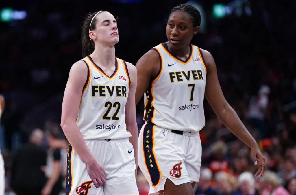Indiana Fever star Caitlin Clark reacts to a possible re-injury as she exits a 2025 WNBA game next to teammate Aliyah Boston.