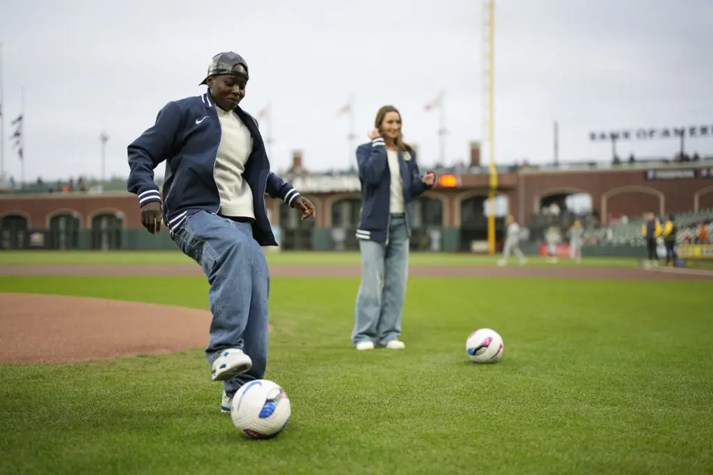 Bay FC stars Racheal Kundananji and Dorian Bailey kick around a ball on the MLB's San Francisco Giants' field at Oracle Park.