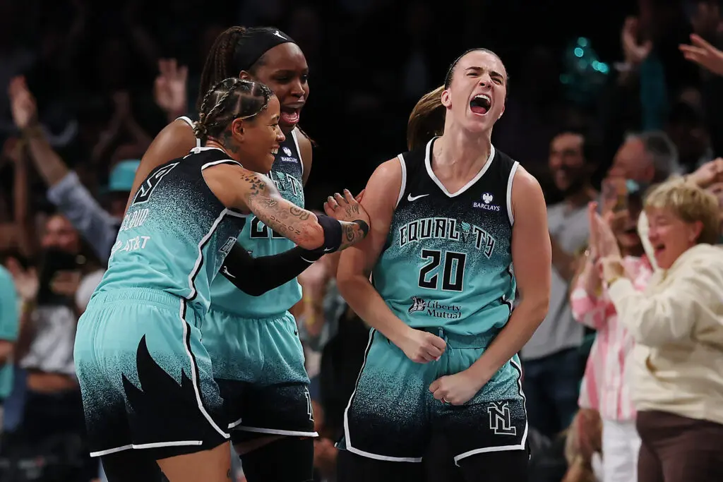 Natasha Cloud and Kennedy Burke celebrate a game-clinching three-point shot from their New York Liberty teammate Sabrina Ionescu.