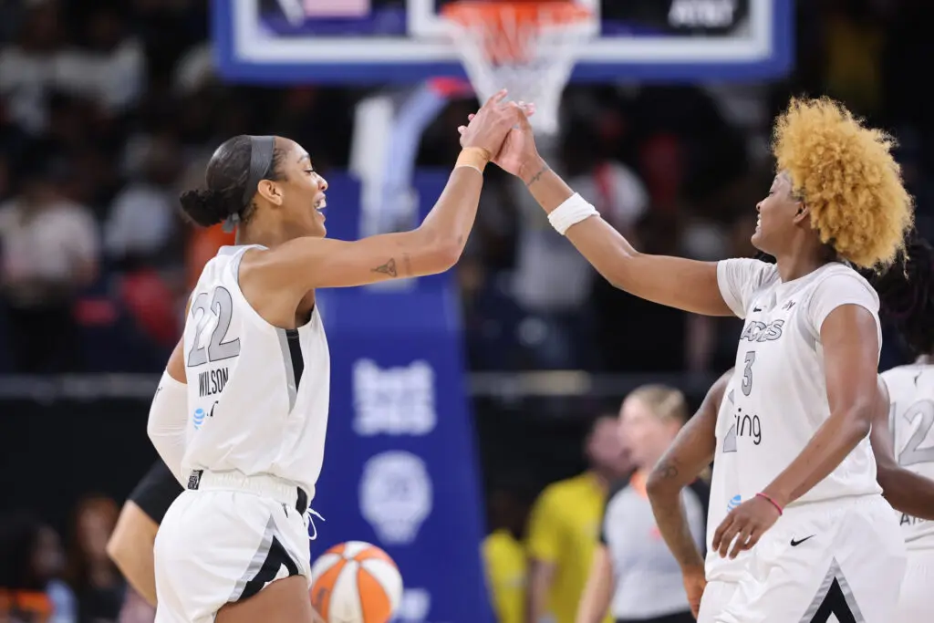 Las Vegas Aces center A'ja Wilson and forward NaLyssa Smith high-five after a 2025 WNBA game.