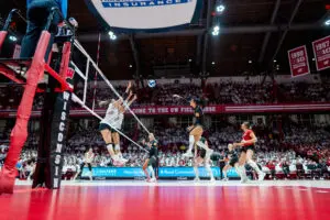 Wisconsin volleyball players leap to block a kill from rival Nebraska during a 2024 NCAA match.