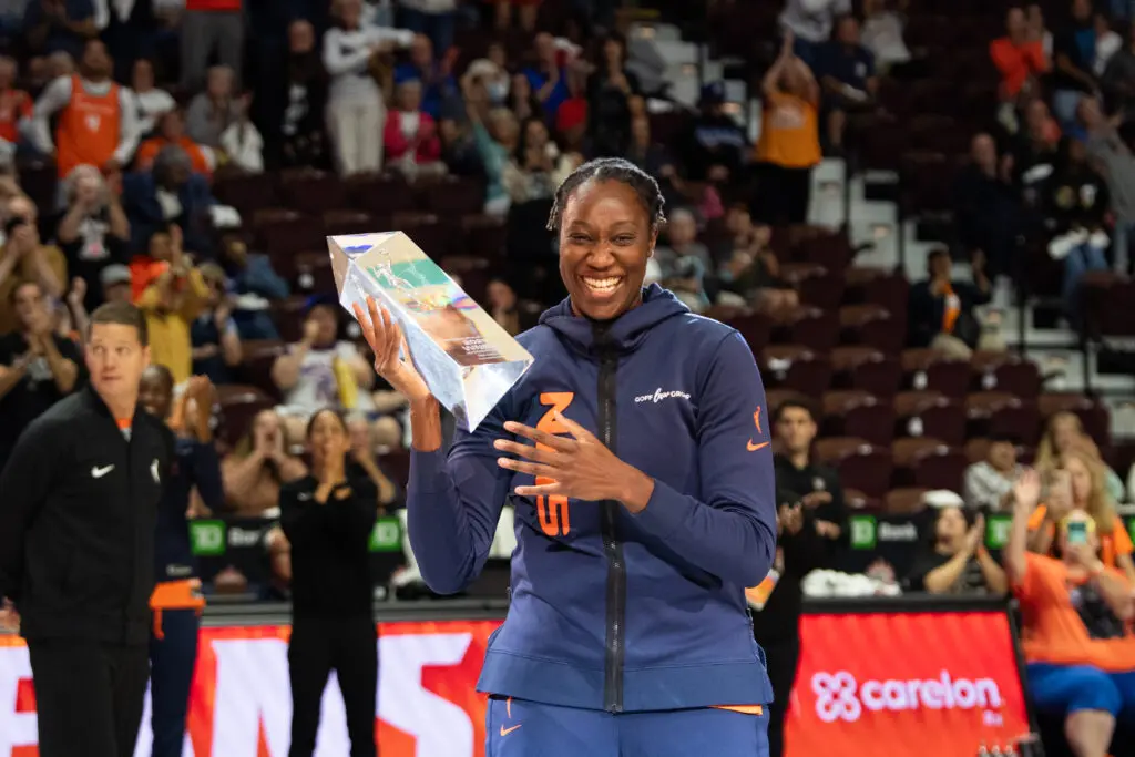 Connecticut Sun star Tina Charles flashes a big smile after receiving her Dawn Staley Community Leadership Award before a 2025 WNBA game.