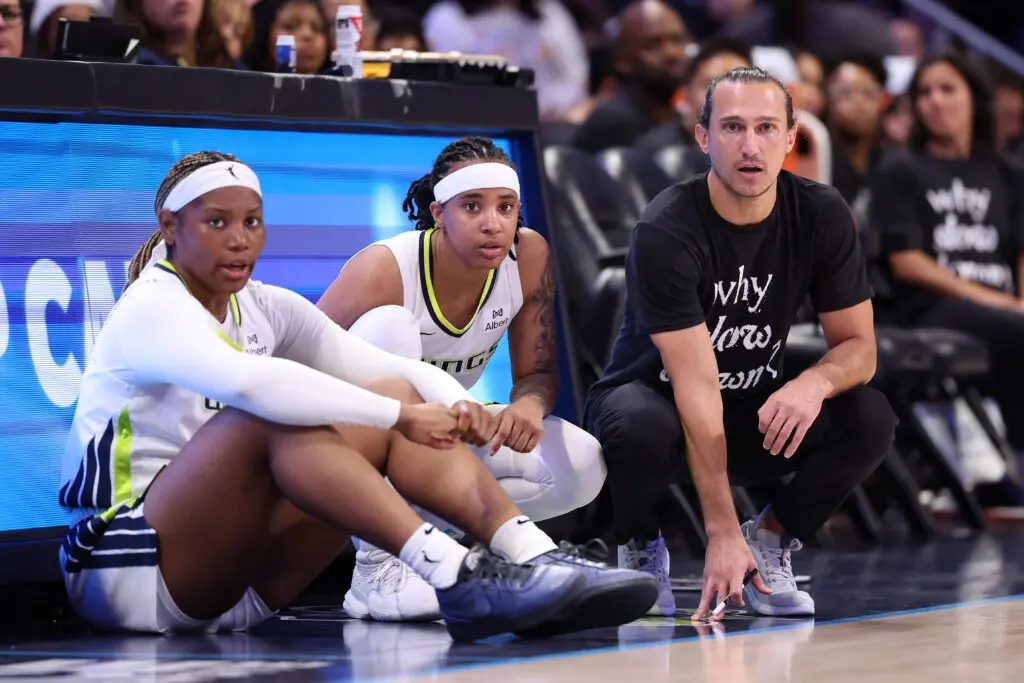 Dallas Wings forward Myisha Hines-Allen, guard Aziaha James, and head coach Chris Koclanes look on from the sideline during a 2025 WNBA game.
