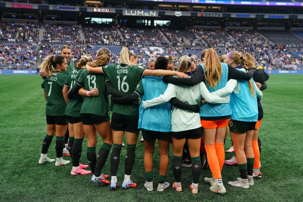 Racing Louisville players huddle before a 2025 NWSL match.