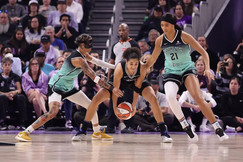 Golden State Valkyries forward Janelle Salaün controls the ball between New York Liberty guard Natasha Cloud and forward Isabelle Harrison during a 2025 WNBA game.