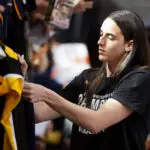 Indiana Fever star Caitlin Clark signs autographs before a 2025 WNBA game.