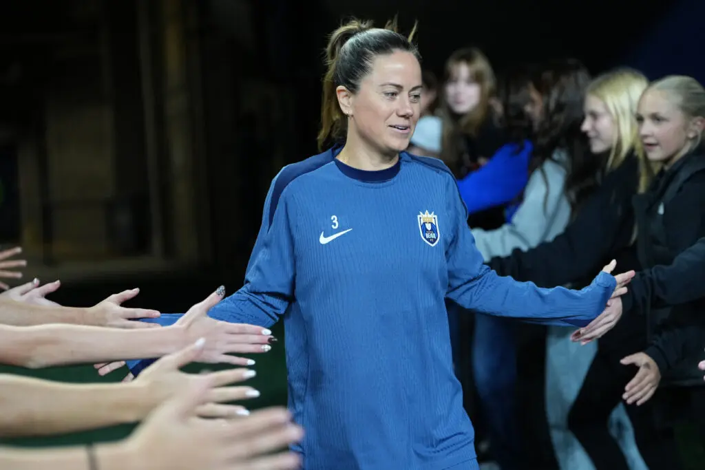 Seattle Reign defender Lauren Barnes gives high-fives to fans while entering the pitch to warm up for a 2025 NWSL match.