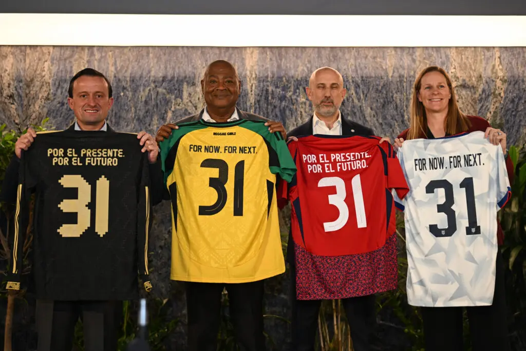 Federation presidents Mikel Arriola (Mexico), Michael Ricketts (Jamaica), Osael Maroto (Costa Rica), and Cindy Parlow Cone (US Soccer) hold up jerseys during their 2031 FIFA Women's World Cup joint hosting announcement.