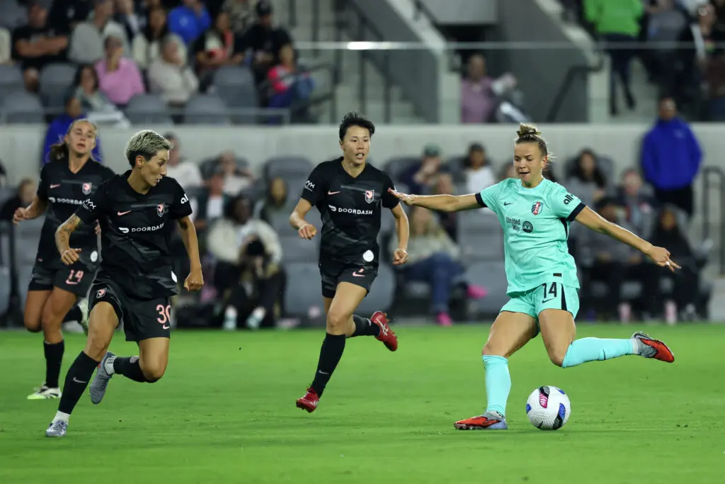 Kansas City Current midfielder Claire Hutton controls the ball with Angel City defenders in pursuit during a 2025 NWSL match.