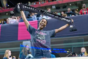 An Atlanta United fan holds up a "Celebrate Women In Sports" scarf during a 2025 MLS match.