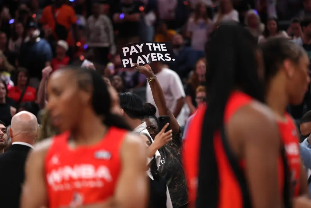 A fan holds a sign saying "Pay the players" during the 2025 WNBA All-Star Game.