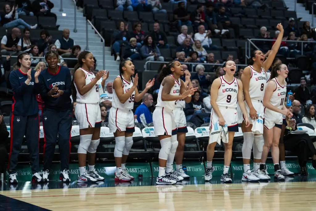 UConn players celebrate a play from the sideline during a 2025/26 NCAA women's basketball preseason exhibition game.