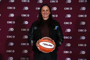 New Toronto Tempo head coach Sandy Brondello smiles while holding a basketball at a press conference.