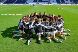 The University of Washington Huskies kneel together before the 2025 Big Ten women's soccer tournament final.