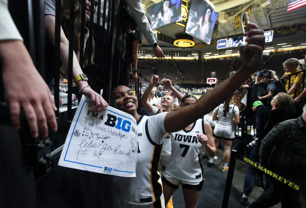 Iowa guard Journey Houston takes a selfie with fans after a 2025/26 NCAA basketball game.