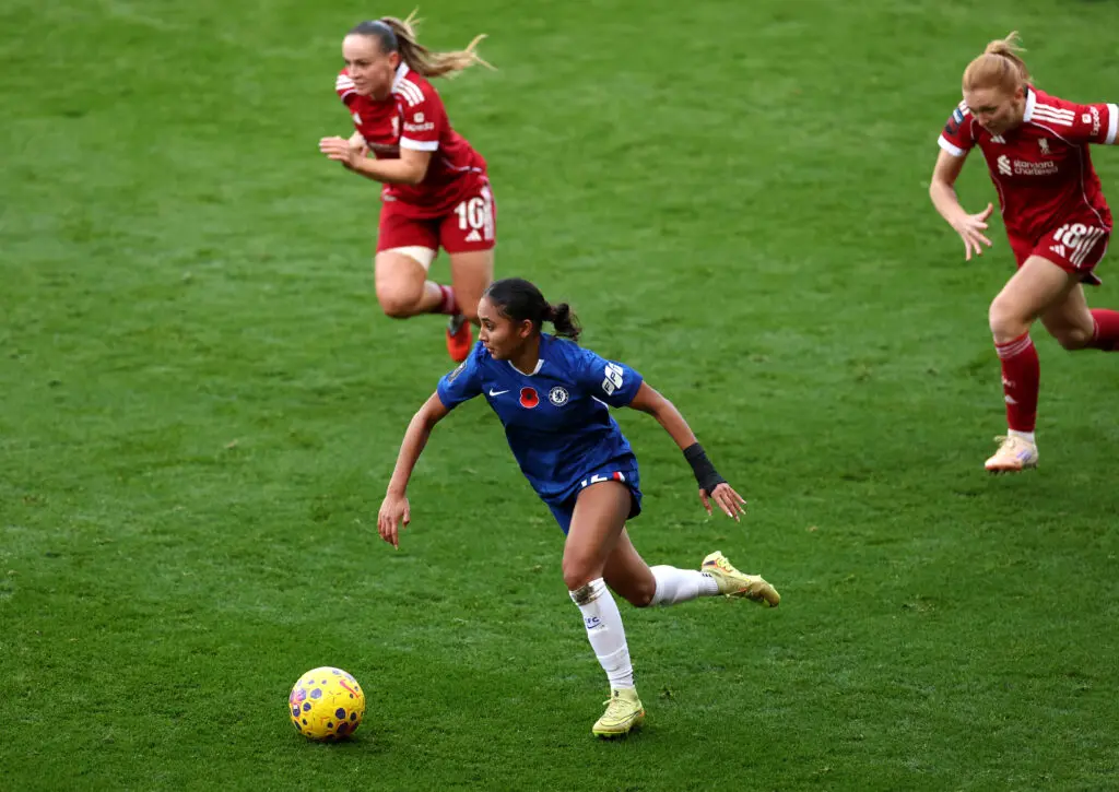 A pair of Liverpool defenders chase Chelsea FC forward Alyssa Thompson as she takes the ball up the pitch during a 2025/26 WSL match.