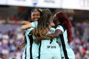 Gotham FC striker Esther and defender Mandy Freeman hug attacker Jaedyn Shaw after her game-winning goal in the 2025 NWSL semifinals