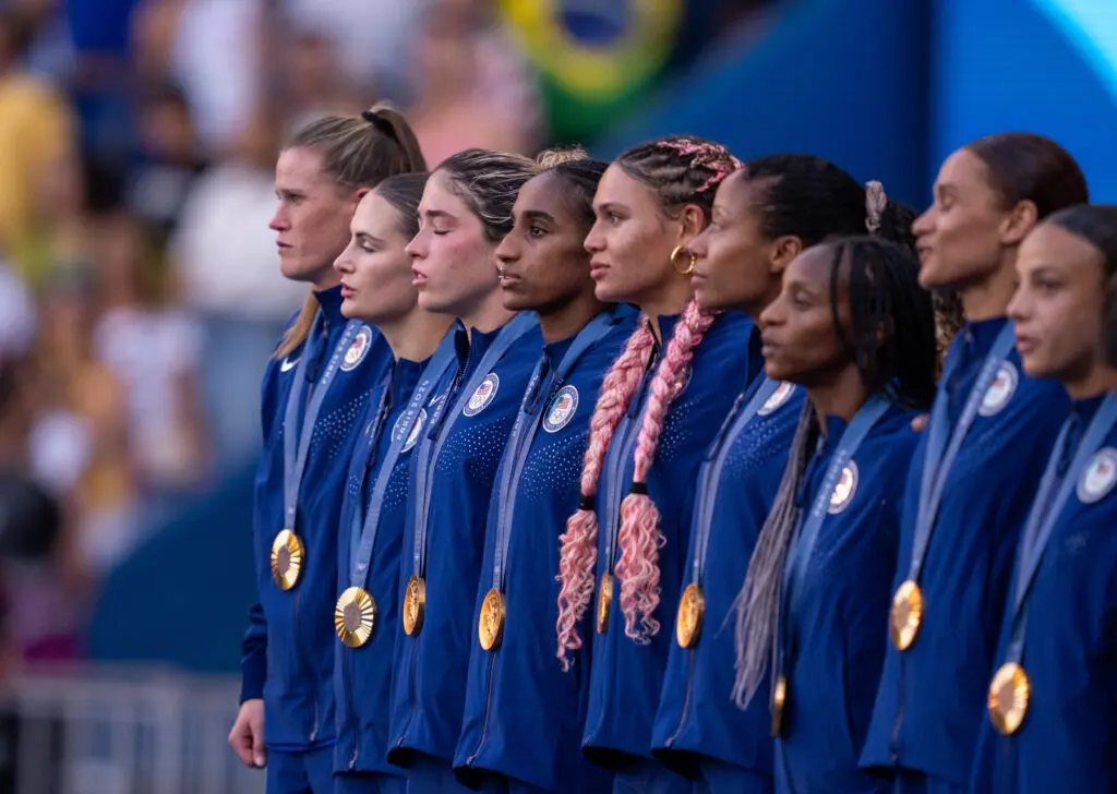 The USWNT stand on the podium wearing their gold medals at the 2024 Paris Olympics.
