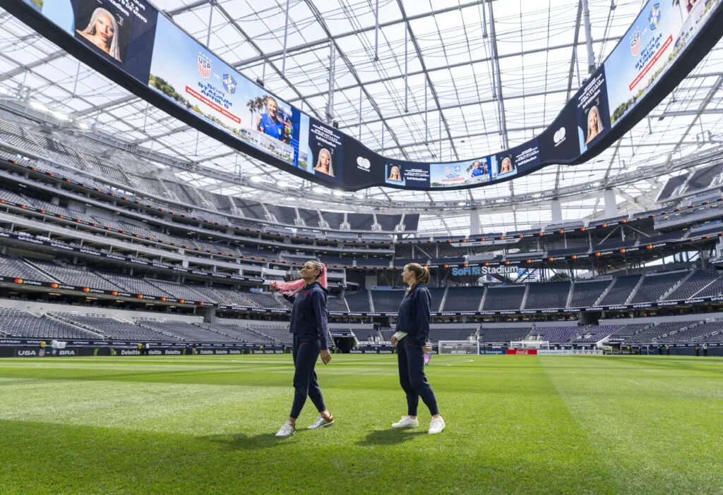 USWNT forward Trinity Rodman and defender Tara McKeown stand on the SoFi Stadium field before a 2025 friendly.