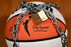 An official WNBA basketball sits with a lock and chain around it to warn of a potential league lockout without a new CBA.