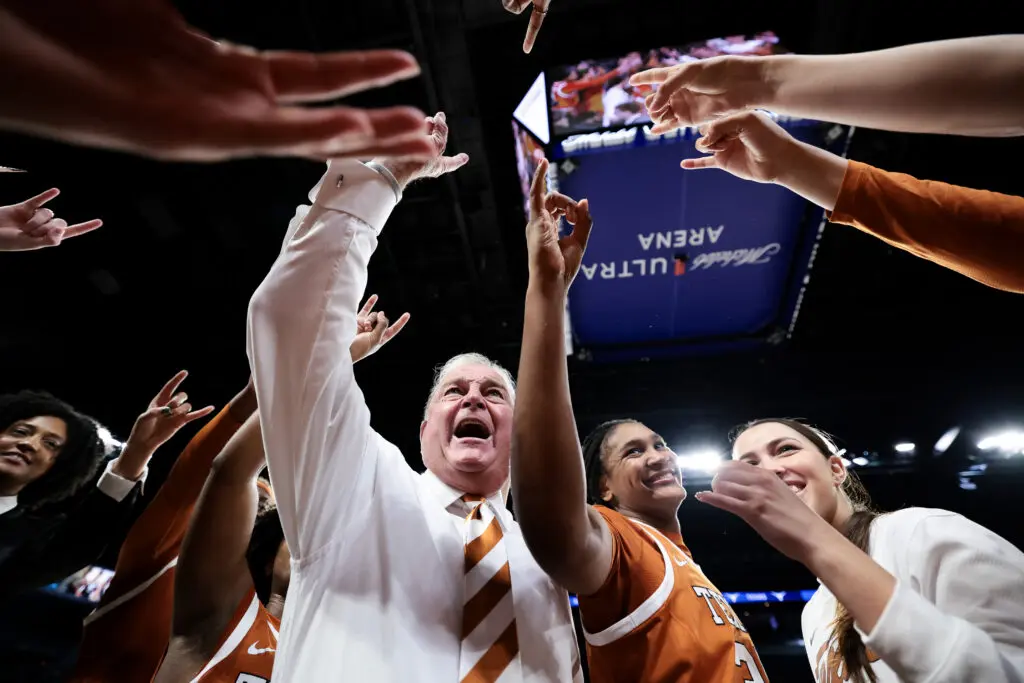 Longtime NCAA basketball head coach Vic Schaefer and his Texas Longhorns celebrate their 2025 Players Era Championship title in a team huddle.