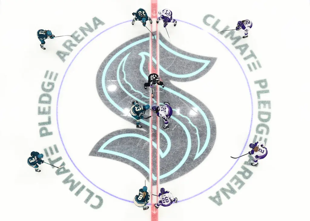 An overhead view of the puck drop at center ice for the 2025 inaugural PWHL game of the Seattle Torrent.