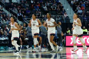 UConn stars KK Arnold, Sarah Strong, Serah Williams, and Azzi Fudd jog to the bench for a timeout during a 2025/26 NCAA basketball game.