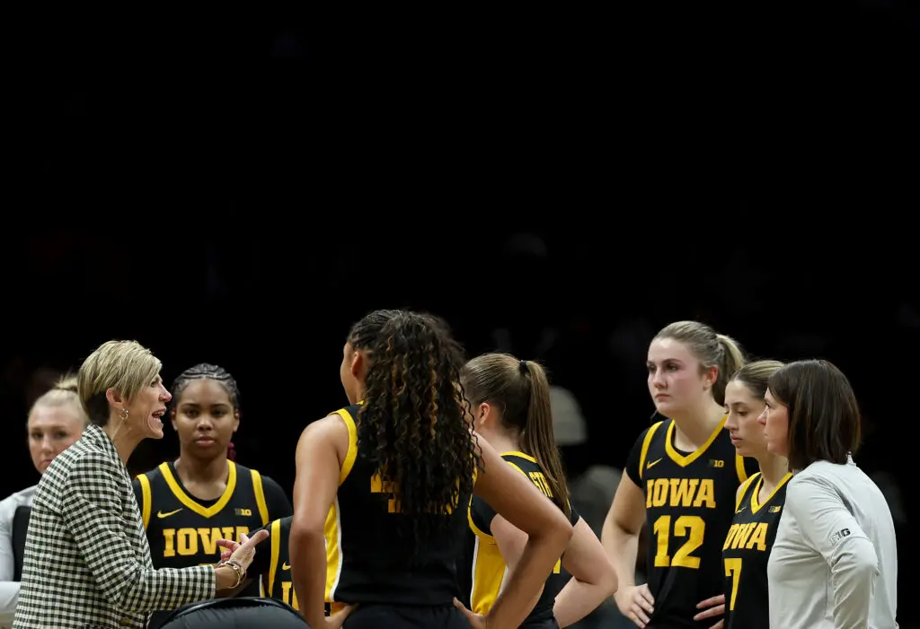 Iowa head coach Jan Jensen talks to her team in a huddle during a 2025/26 NCAA basketball game.