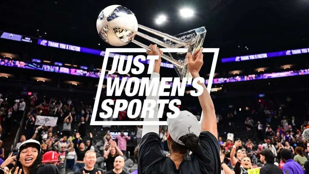 A'ja Wilson holds up the WNBA Championship trophy in front of a crowded stadium.