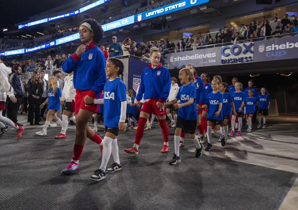 USWNT midfielder Lily Yohannes and defender Emily Sonnett lead the team onto the pitch before the 2025 SheBelieves Cup final.