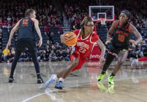 Ohio State sophomore guard Jaloni Cambridge dribbles between Maryland defenders Yarden Garzon and Mir McLean during a 2025/26 NCAA basketball game.