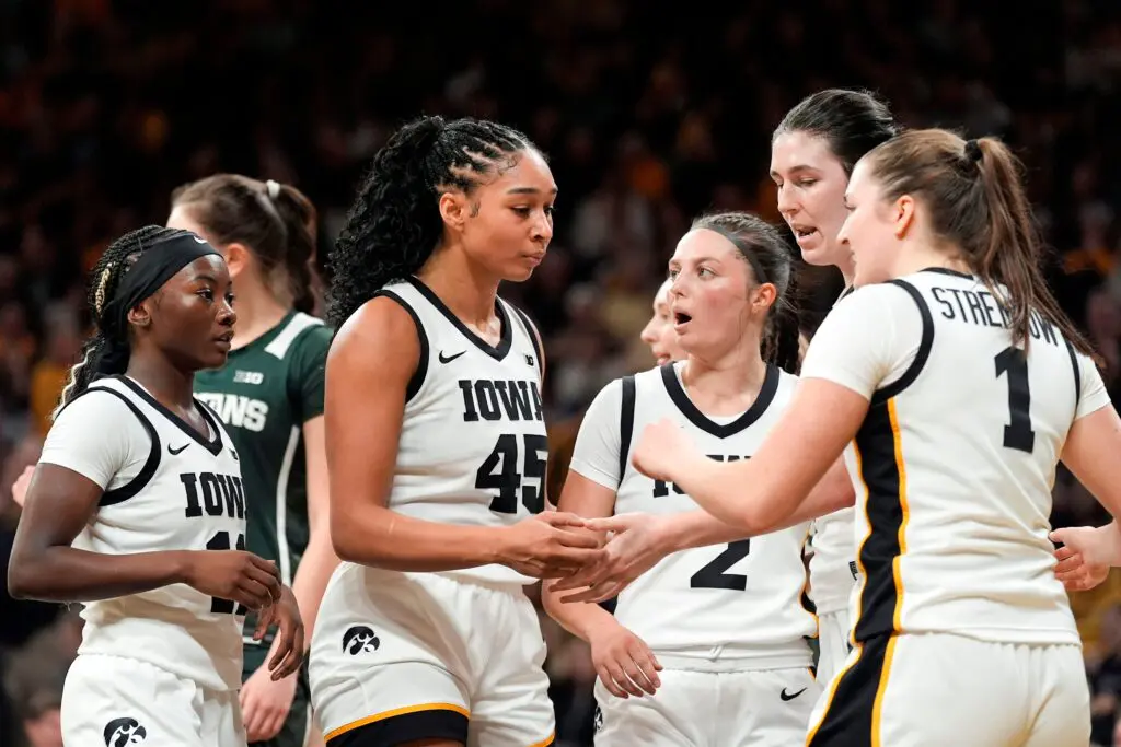 Iowa guard Chit-Chat Wright, forward Hannah Stuelke, guard Taylor McCabe, center Ava Heiden, and guard Taylor Stremlow huddle during a 2025/26 NCAA basketball game.