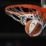 An official WNBA basketball clears the net after a successful shot prior to a 2025 season game.