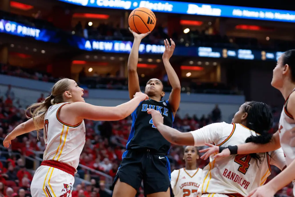 Surrounded by Louisville defenders, Duke guard Riley Nelson puts up a jump shot during a 2025/26 NCAA basketball game.