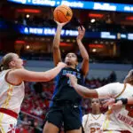 Surrounded by Louisville defenders, Duke guard Riley Nelson puts up a jump shot during a 2025/26 NCAA basketball game.