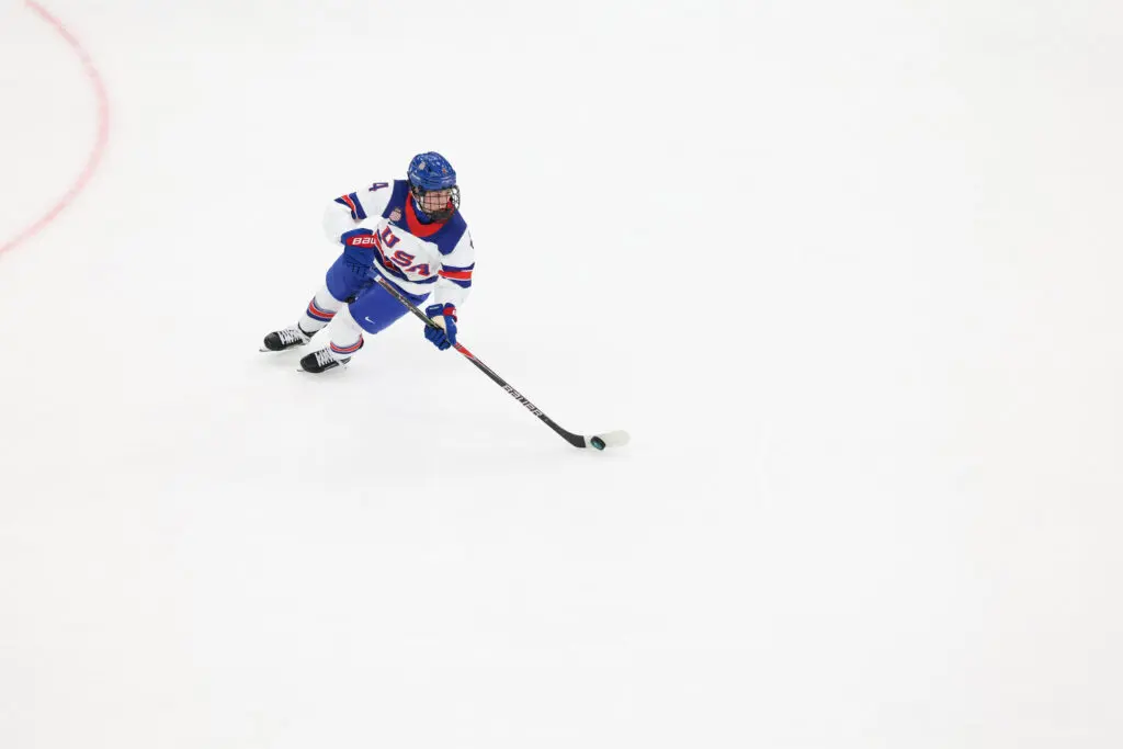 USA hockey defender Caroline Harvey controls the puck during a group-stage game at the 2026 Winter Olympics.