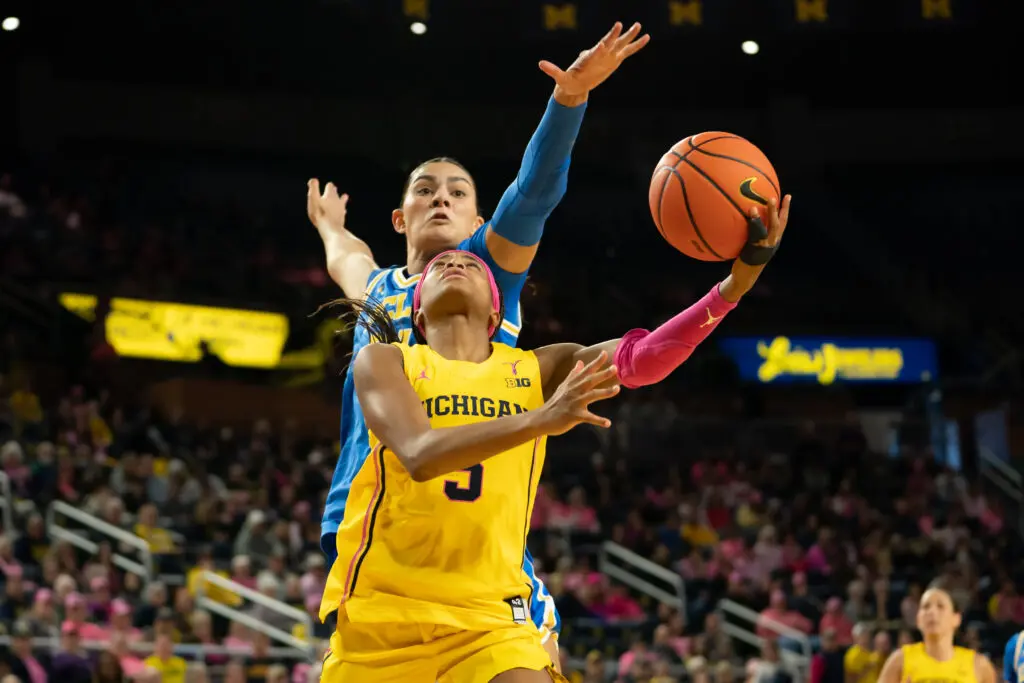Michigan guard Mila Holloway lays up a ball as UCLA center Lauren Betts looks to block her during a 2025/26 NCAA basketball game.