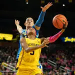 Michigan guard Mila Holloway lays up a ball as UCLA center Lauren Betts looks to block her during a 2025/26 NCAA basketball game.
