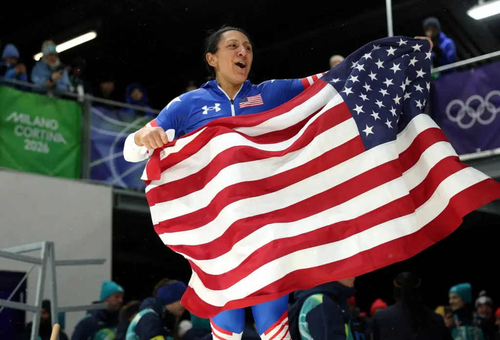 Decorated Team USA bobsled star Elana Meyers Taylor waves a US flag while celebrating her career-first Olympic gold medal at the 2026 Winter Games.