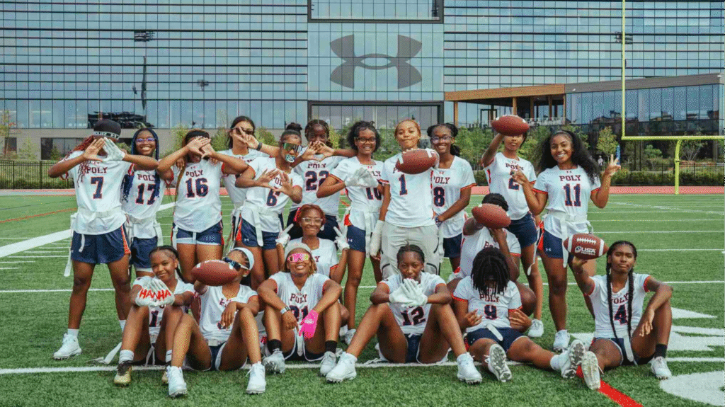 The Baltimore Polytechnic Institute girls varsity flag football team poses on the Under Armour Stadium field outside the sportswear company's Maryland headquarters.