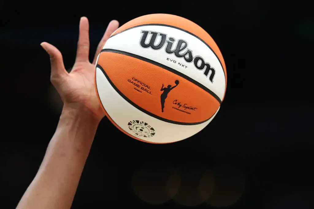 A hand reaches up to tip off a WNBA basketball during a 2024 game.