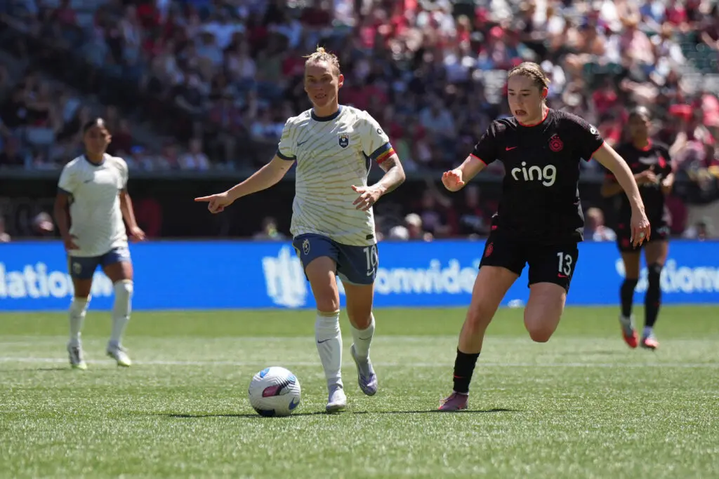 Seattle Reign star Jess Fishlock dribbles the ball as Portland Thorns midfielder Olivia Moultrie challenges during a 2025 NWSL match.